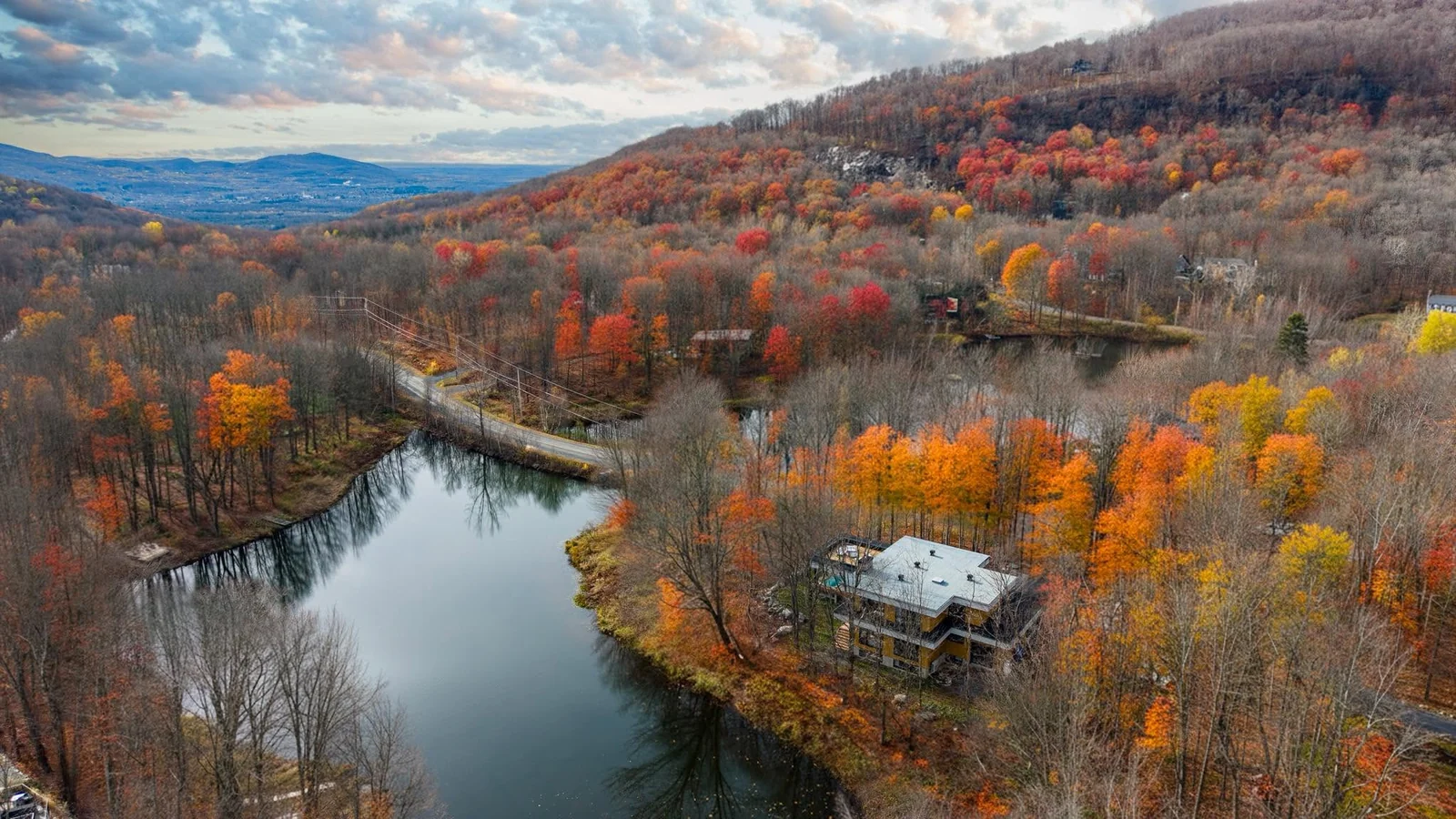 Vue aérienne d’une propriété au bord d’un lac entouré d’arbres en automne