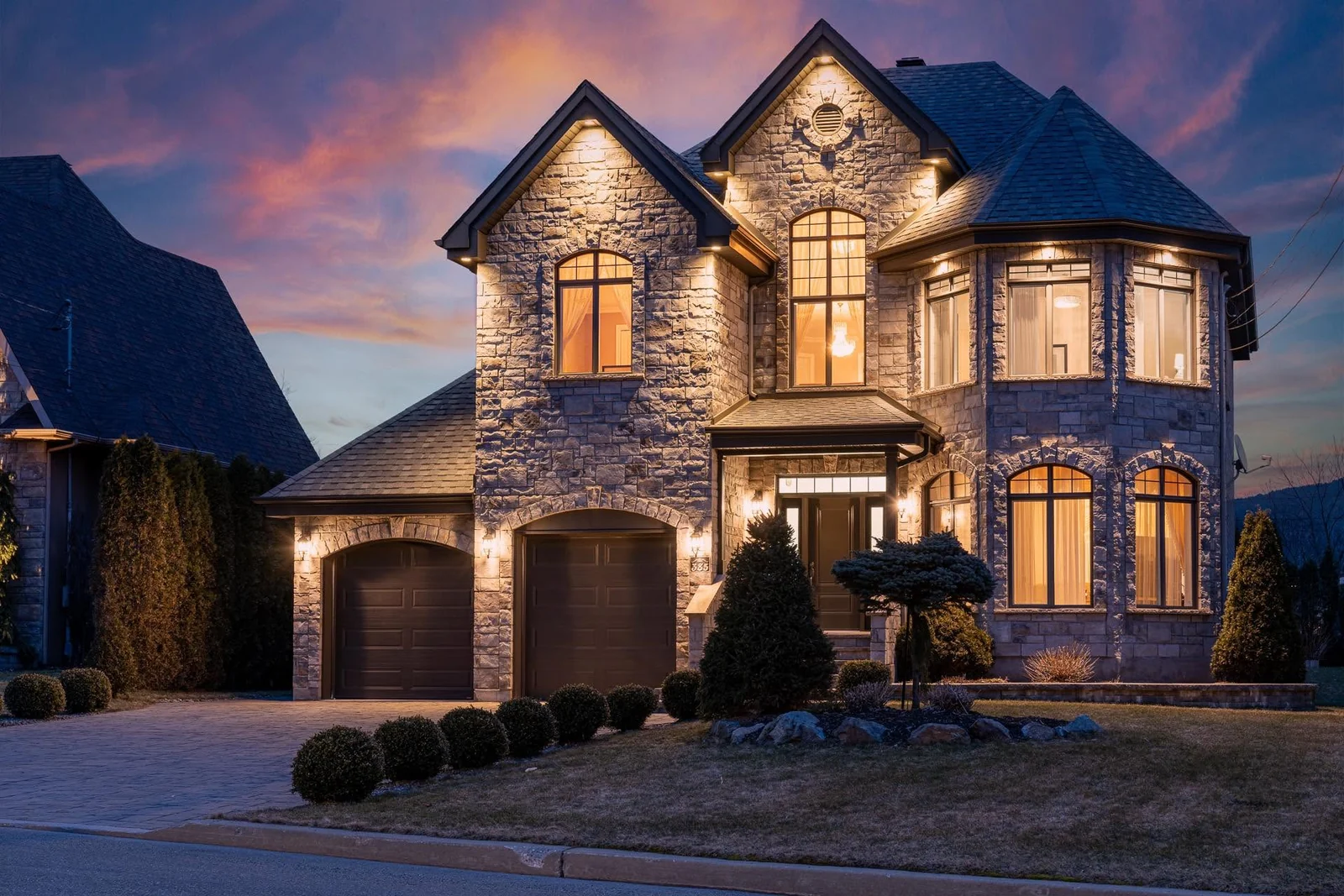 Stone house with illuminated windows beneath a twilight sky